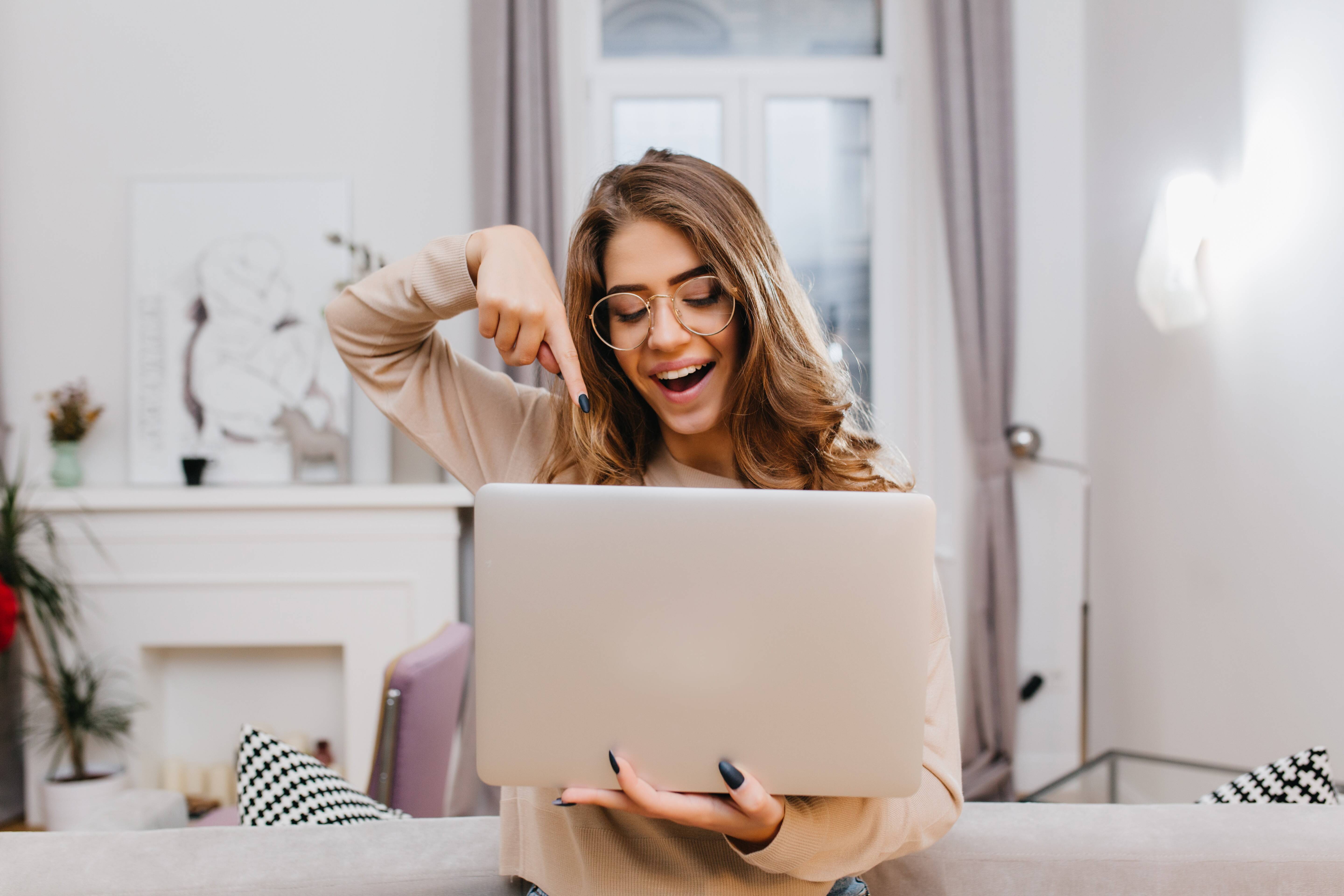 interested-girl-with-trendy-manicure-fooling-around-home-during-photoshoot-with-laptop.jpg