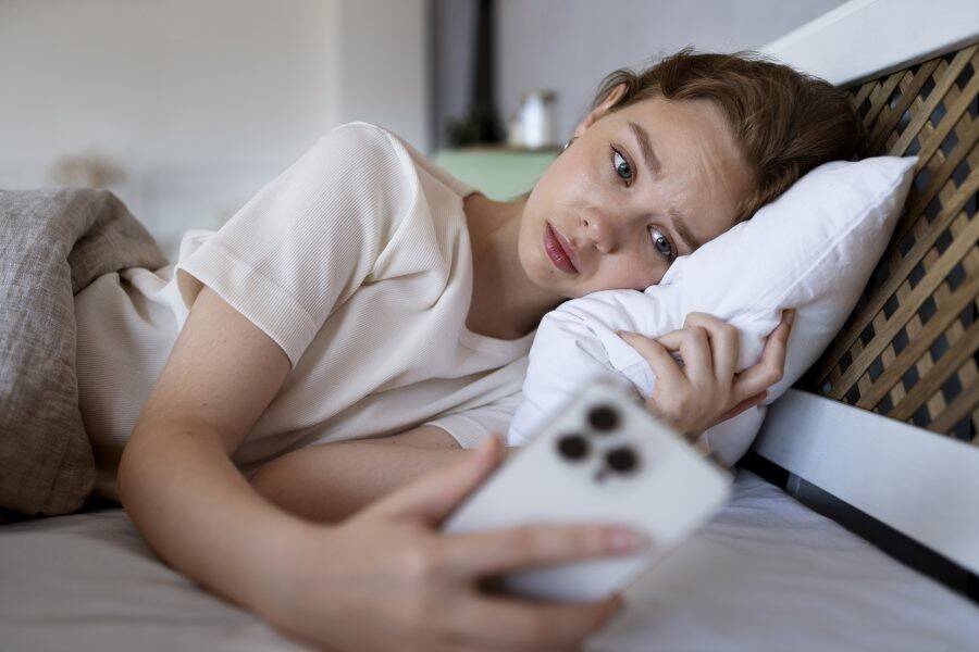 medium-shot-anxious-woman-in-bed-with-phone-e1658840088854.jpg