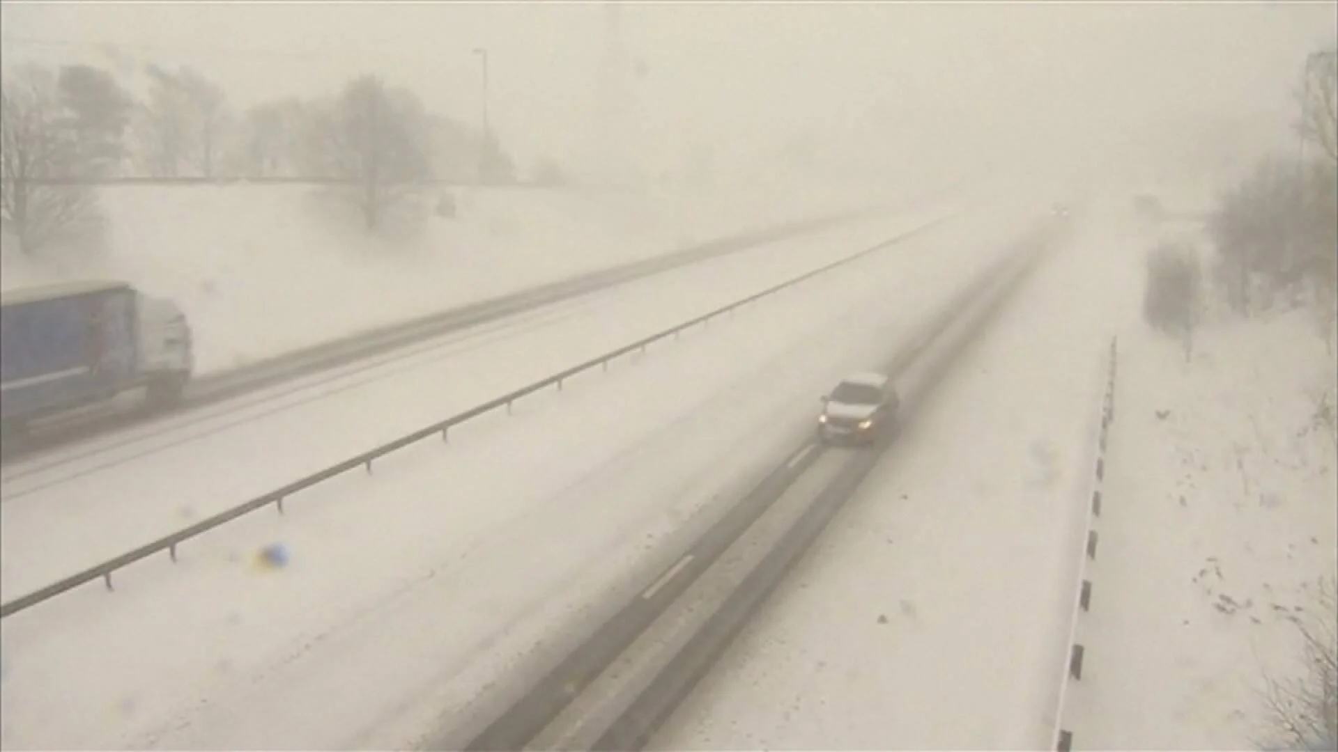 Vehículos circulan por una autopista completamente nevada bajo condiciones de visibilidad reducida por tormenta de nieve.