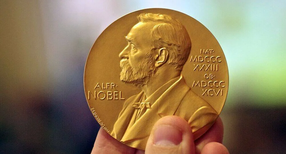 Mano sosteniendo la medalla dorada del Premio Nobel con el perfil en relieve de Alfred Nobel.