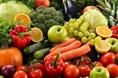 Abundante surtido de frutas y verduras frescas: tomates, zanahorias, brócoli, manzanas, uvas, pimientos y más.