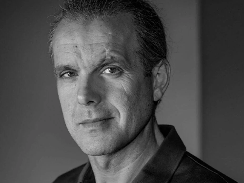 Retrato en blanco y negro de un hombre de mediana edad con cabello peinado hacia atrás y expresión serena.