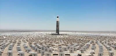 Torre de concentración solar rodeada de miles de heliostatos en un extenso campo desértico.