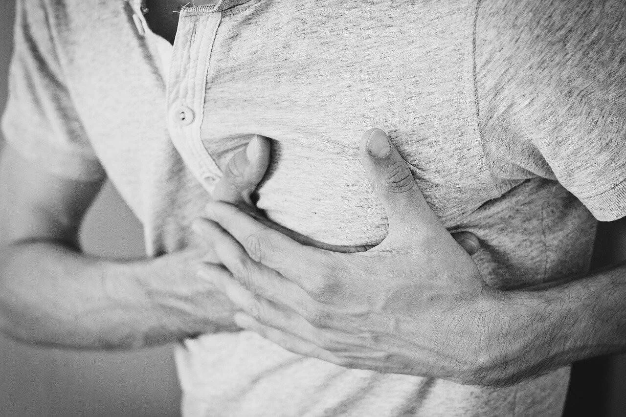 Una persona se lleva ambas manos al pecho, gesto asociado a dolor torácico o infarto.