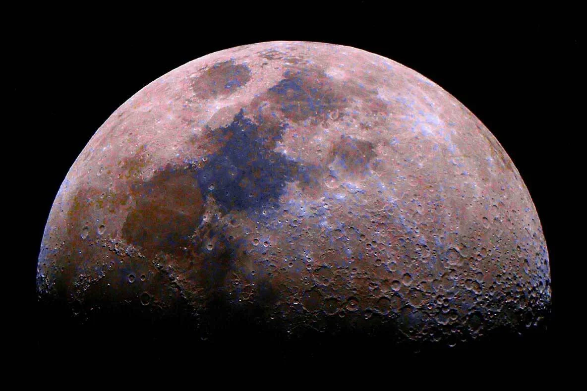 Vista detallada de la Luna en fase cuarto creciente con colores realzados que revelan la composición mineral de su superficie.