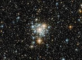 Cúmulo de estrellas brillantes rodeado de miles de puntos de luz sobre el fondo negro del espacio.