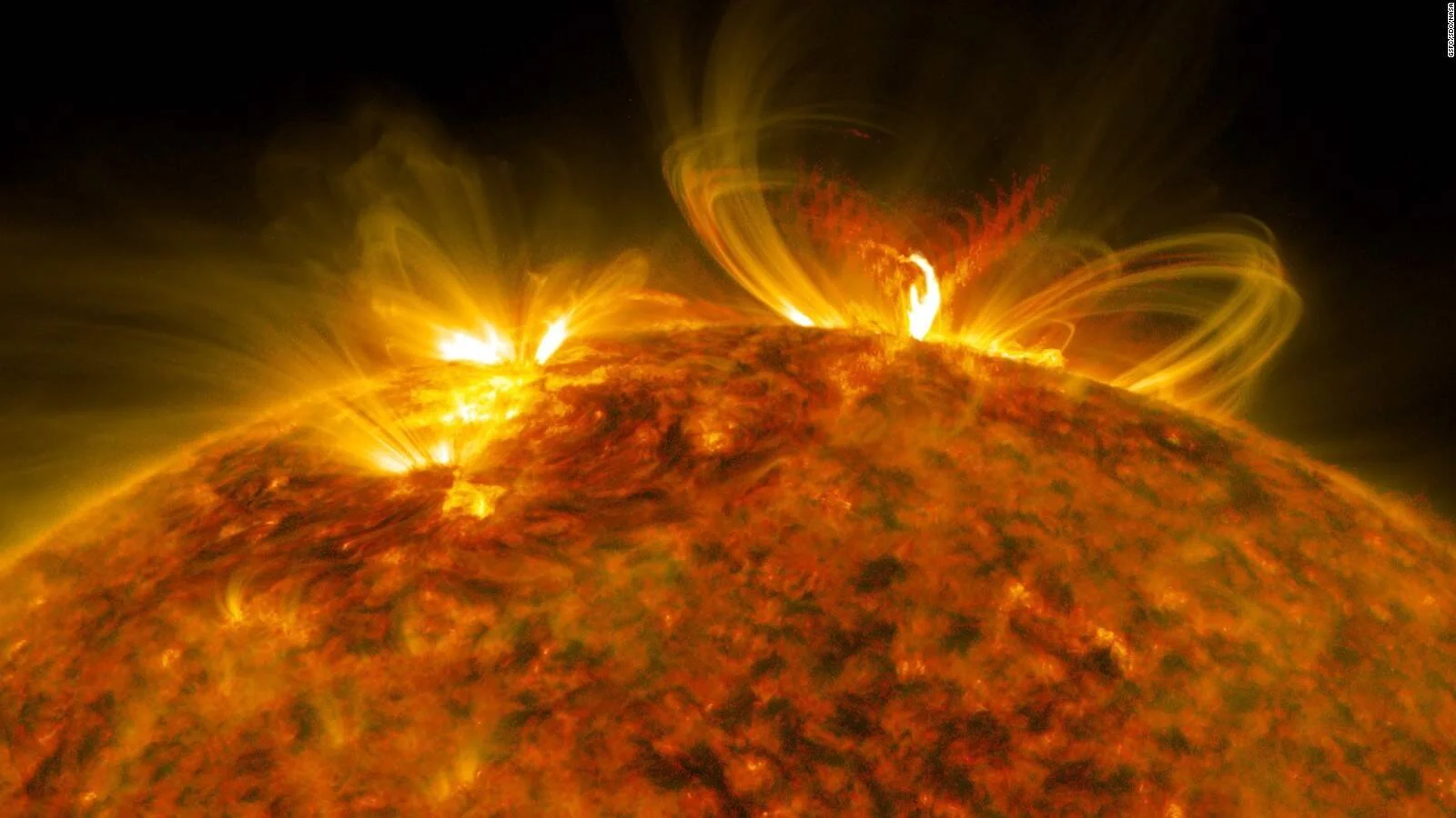 Imagen satelital de la superficie solar con prominentes llamaradas y bucles de plasma magnético emergiendo de la corona.