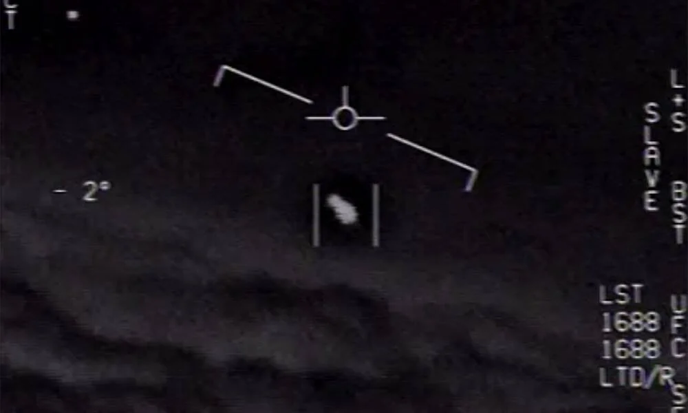 Pantalla de sistema de rastreo militar que muestra un objeto no identificado volador sobre nubes, con datos de telemetría superpuestos.
