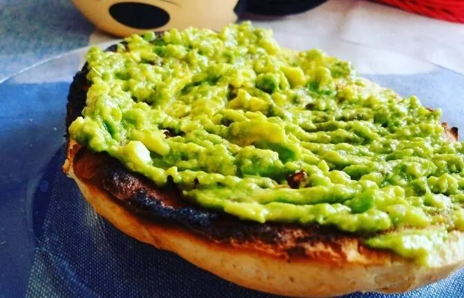 Pan tostado cubierto con abundante guacamole fresco servido sobre papel de cocina.