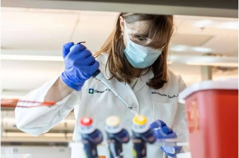 Investigadora con bata, mascarilla y guantes azules manipula muestras con pipeta en un laboratorio de Cleveland Clinic.
