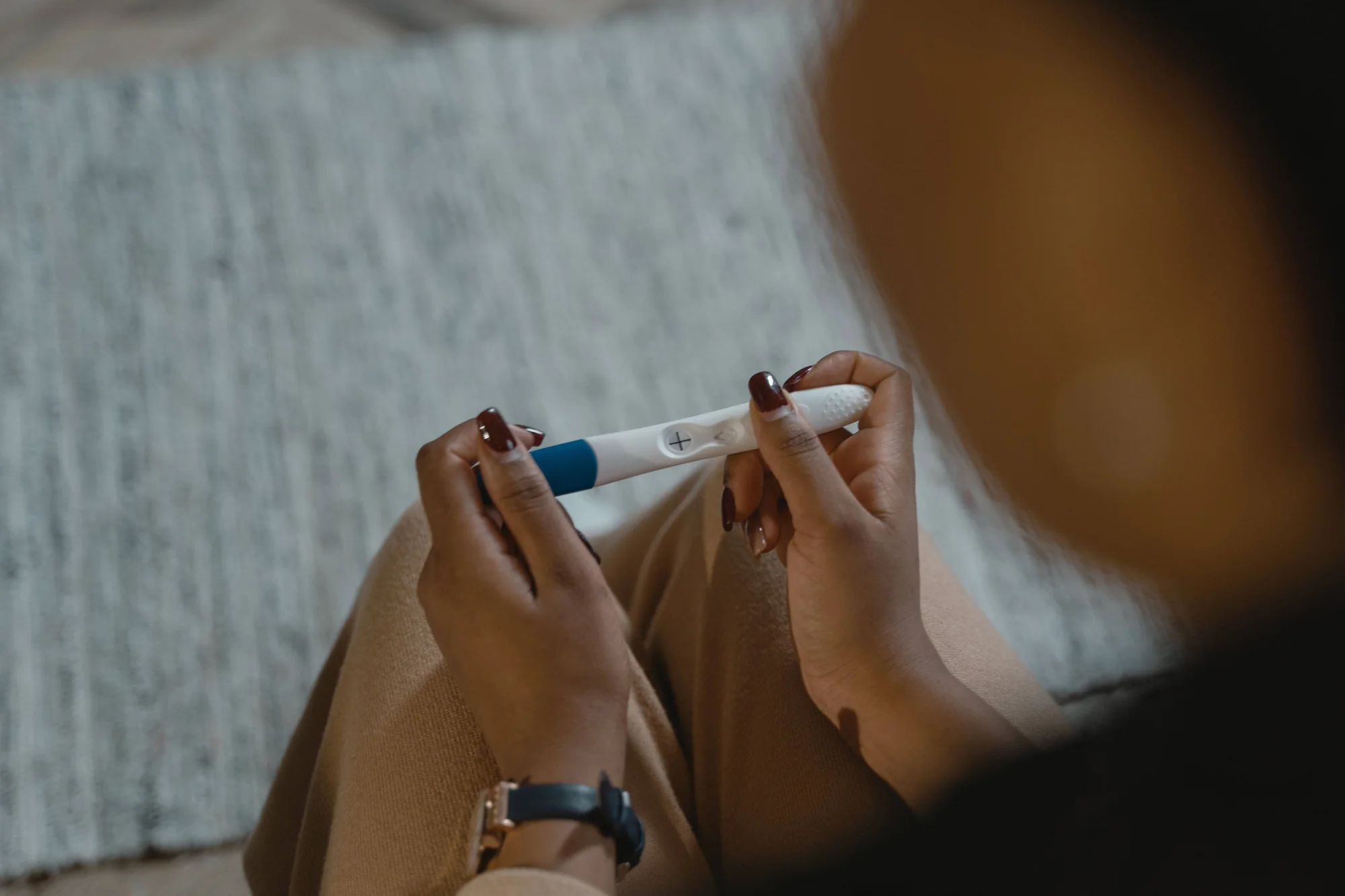 Una mujer observa un test de embarazo con signo positivo entre sus manos.