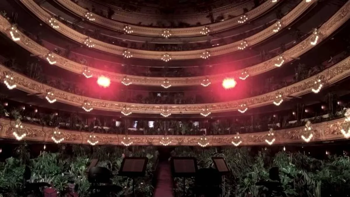 Sala de un teatro de ópera con balcones dorados iluminados y el patio de butacas ocupado por plantas en lugar de público.