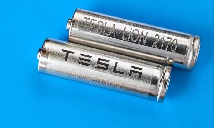 Dos celdas cilíndricas de batería Tesla LiON 2170 de ion-litio sobre fondo azul.