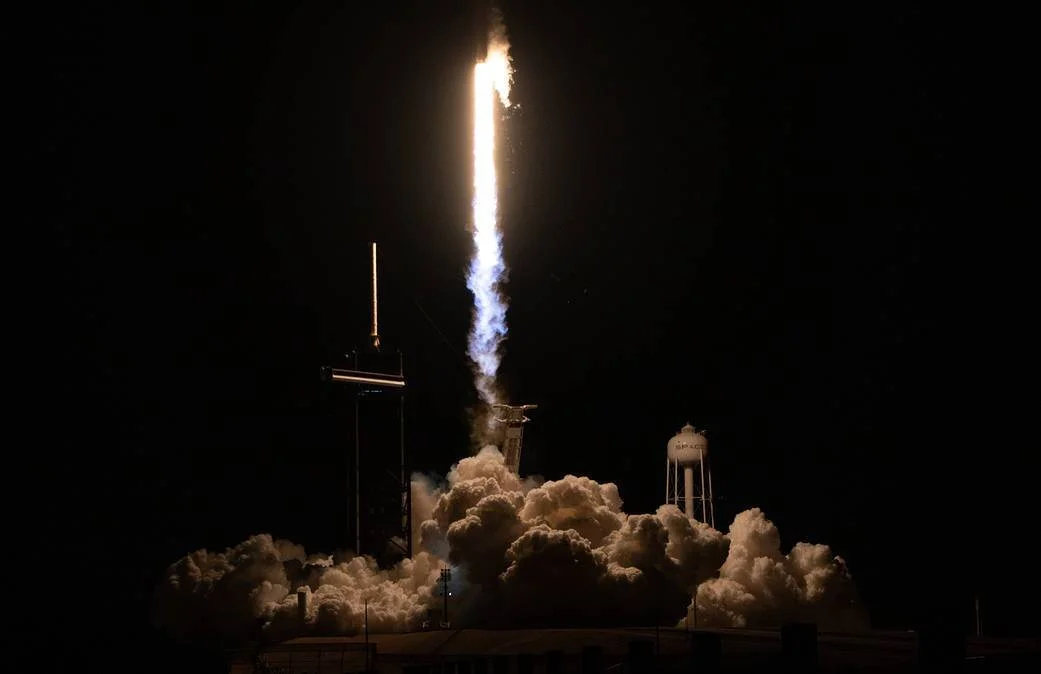Cohete SpaceX despega de noche entre llamas y nubes de vapor desde una plataforma de lanzamiento.