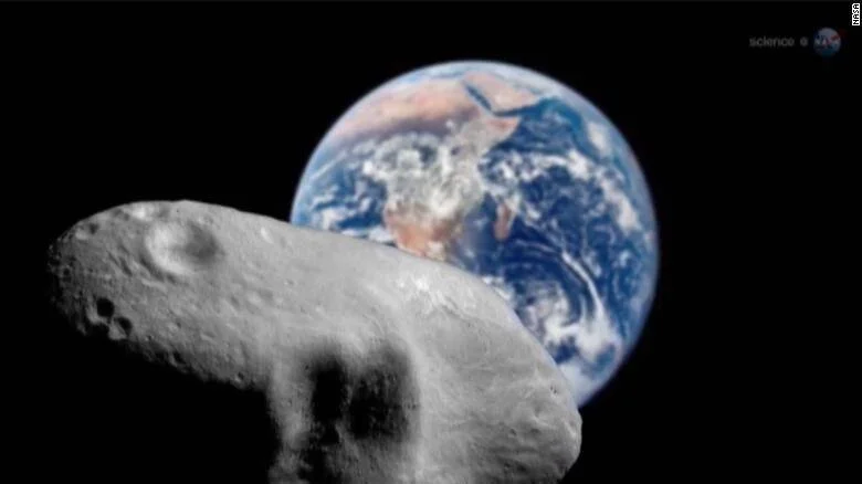 Ilustración de la NASA que muestra un asteroide rocoso en primer plano con la Tierra al fondo en el espacio.