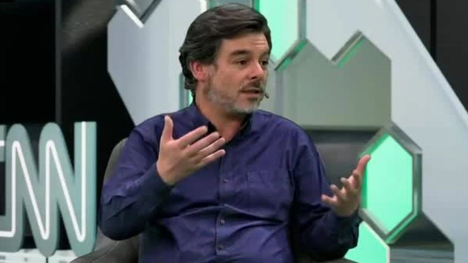 Hombre con camisa azul gesticula mientras habla en un estudio de televisión de CNN.