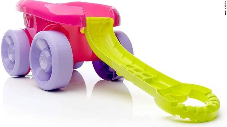 Carrito de juguete infantil de plástico rosa con ruedas lila y mango verde lima, marca Fisher-Price.