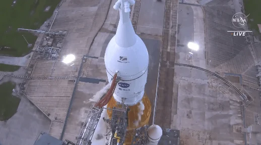 Vista aérea de un cohete de la NASA en la plataforma de lanzamiento, con transmisión en vivo.