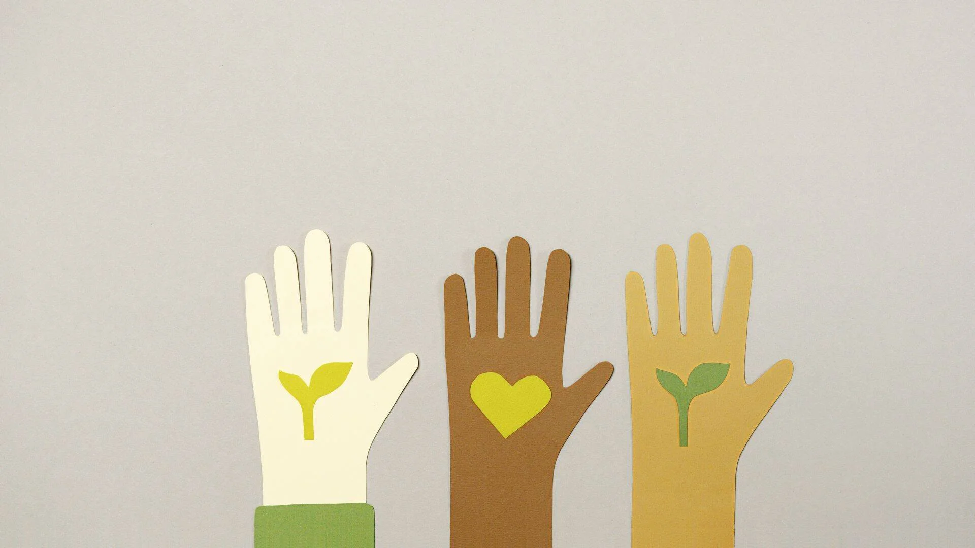 Tres manos de papel de distintos tonos de piel alzadas, con símbolos de brote vegetal y corazón, representando diversidad y compromiso ambiental.