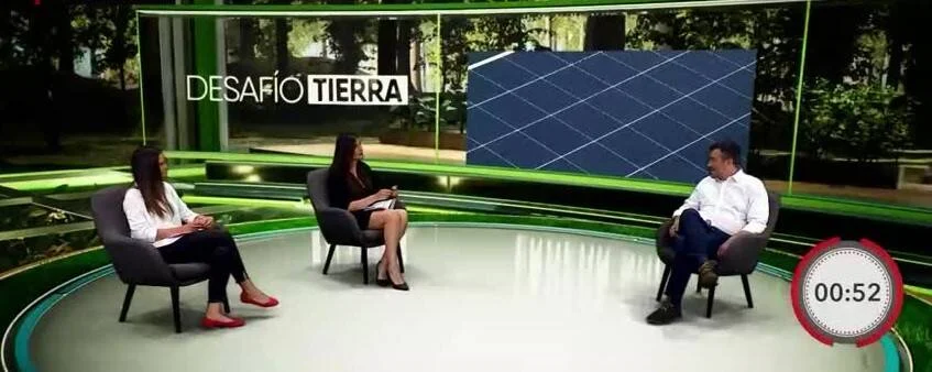 Tres personas sentadas en estudio de televisión del programa 'Desafío Tierra', con panel solar visible en la pantalla de fondo.