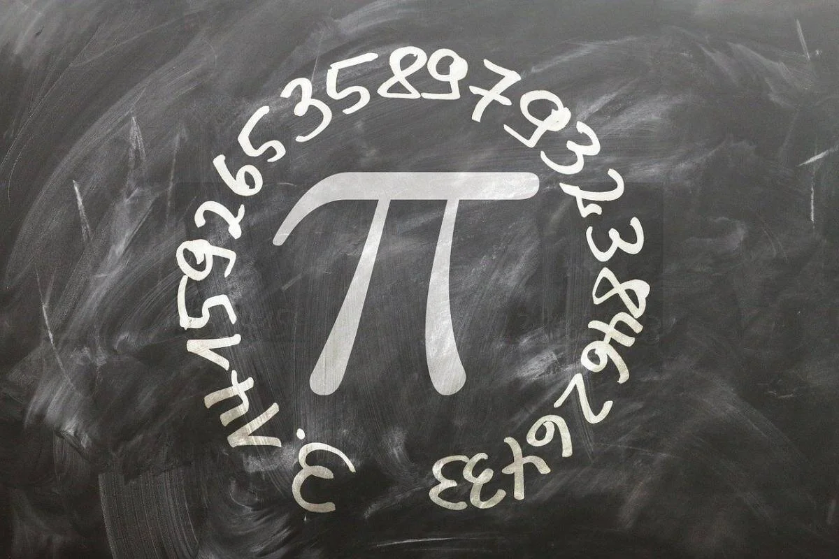 Símbolo matemático π rodeado por sus decimales escritos con tiza blanca sobre una pizarra negra.