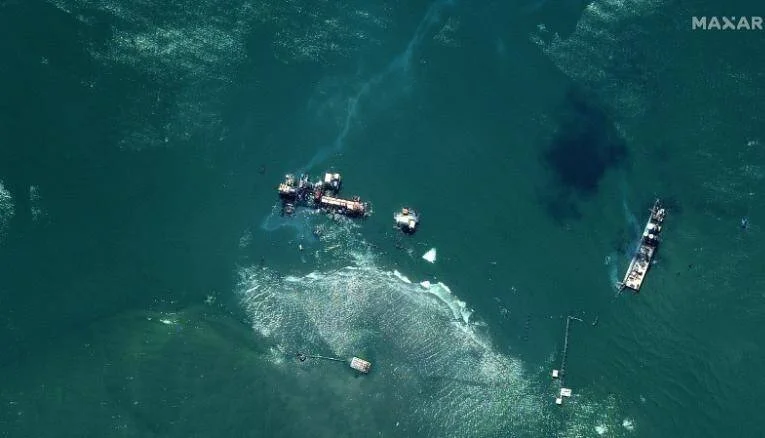 Vista satelital de embarcaciones naufragadas en el mar con manchas oscuras de derrame visible en el agua.