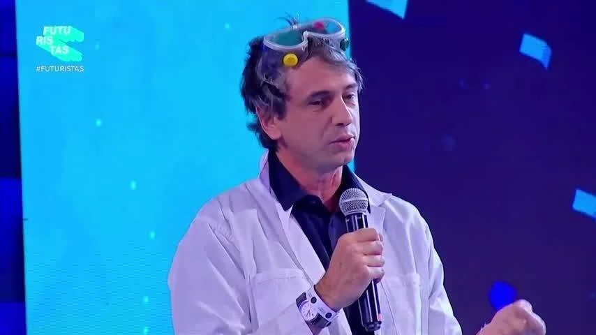 Hombre con guardapolvo blanco y gafas en la cabeza habla con micrófono en el evento #Futuristas.