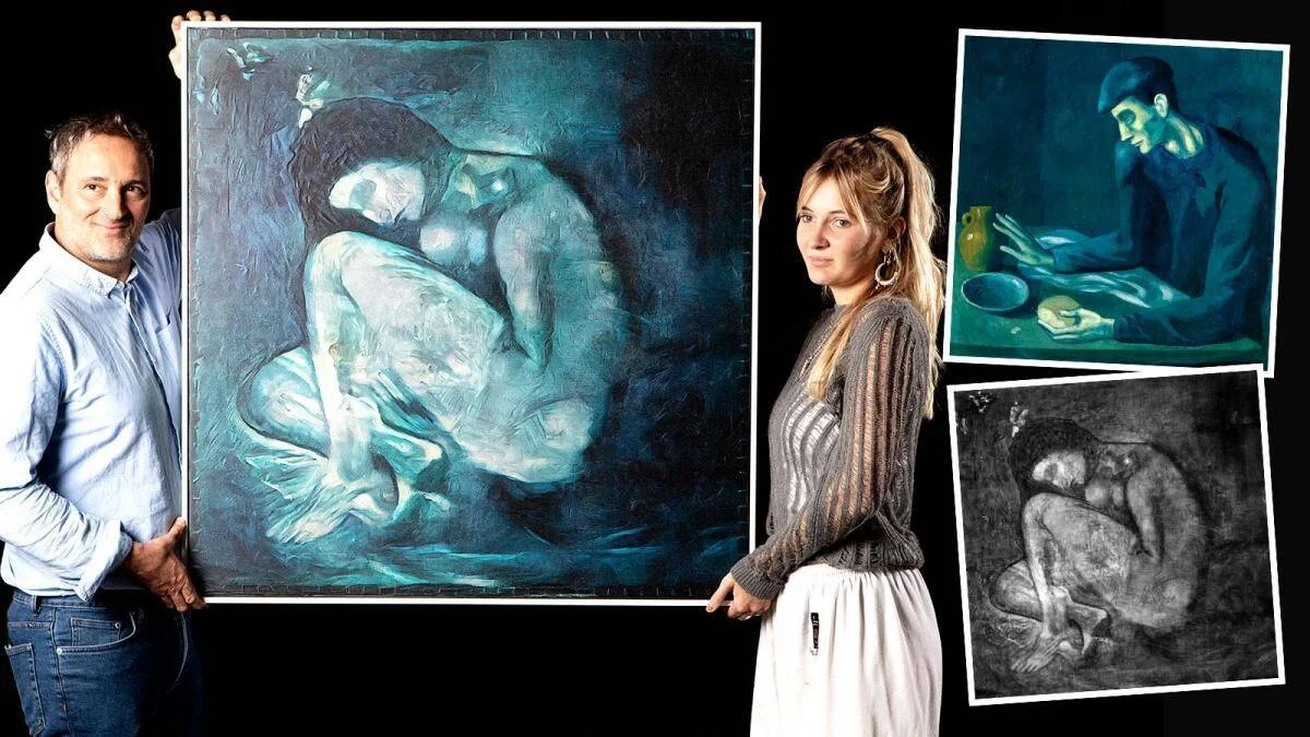 Un hombre y una mujer sostienen una gran pintura de tonos azules con figura femenina, junto a reproducciones de obras del período azul de Picasso.