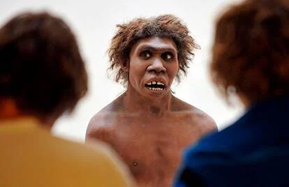 Reconstrucción realista de un homínido prehistórico observado por visitantes durante una exposición.