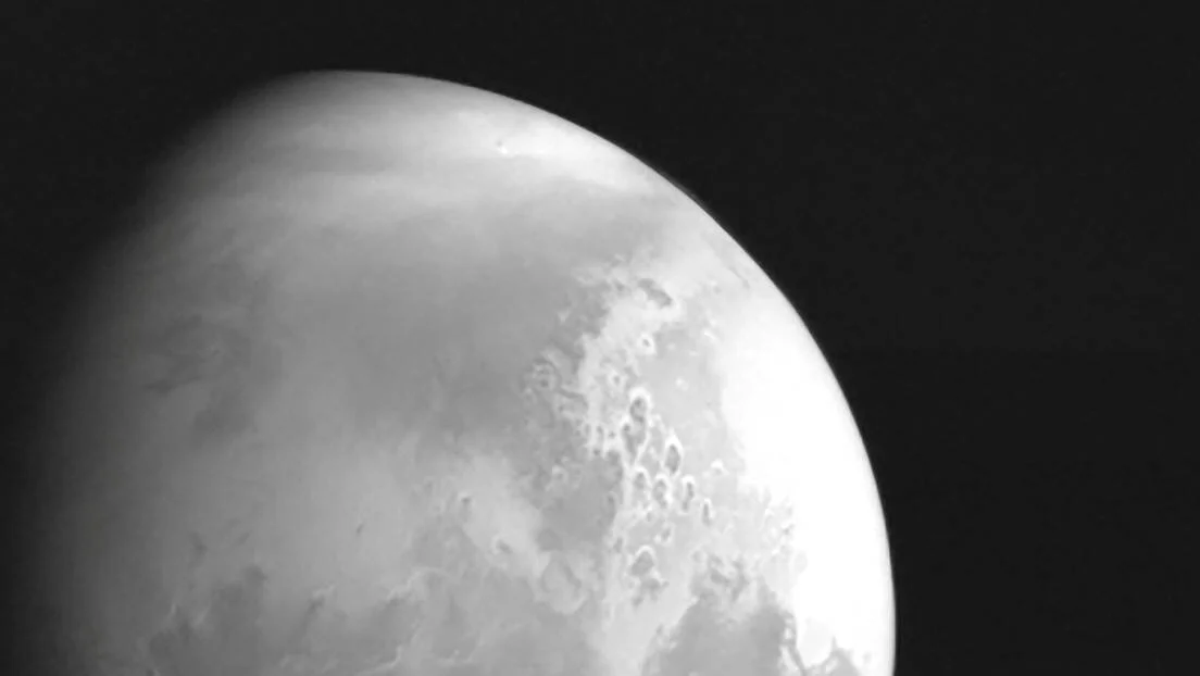 Vista en blanco y negro de la superficie de Marte con cráteres visibles, captada desde el espacio.