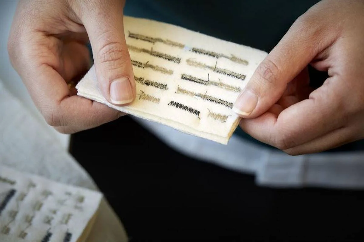 Persona sostiene un pequeño parche de tela flexible con patrones de circuitos electrónicos bordados o impresos en su superficie.