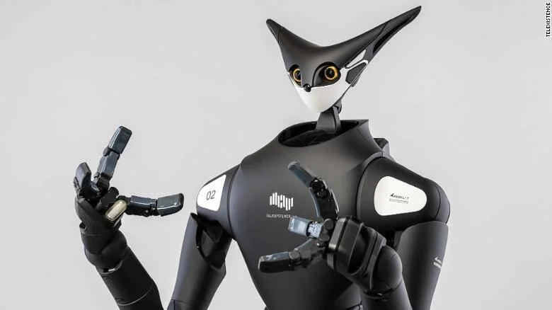 Robot humanoide de color negro con cabeza en forma de ave y ojos dorados, sosteniendo un objeto con su mano articulada.