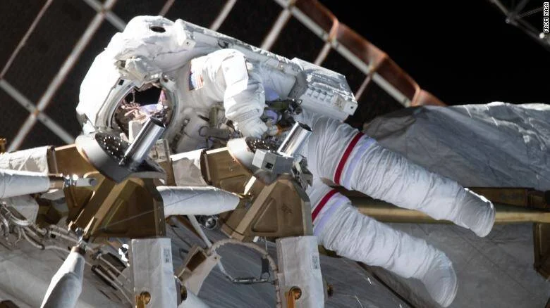 Astronauta con traje espacial blanco realizando una caminata extravehicular en el exterior de la Estación Espacial Internacional.