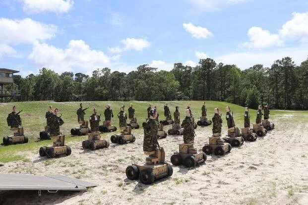 Grupo de soldados con uniforme de camuflaje montados sobre robots de ruedas formados en semicírculo en campo de entrenamiento militar.