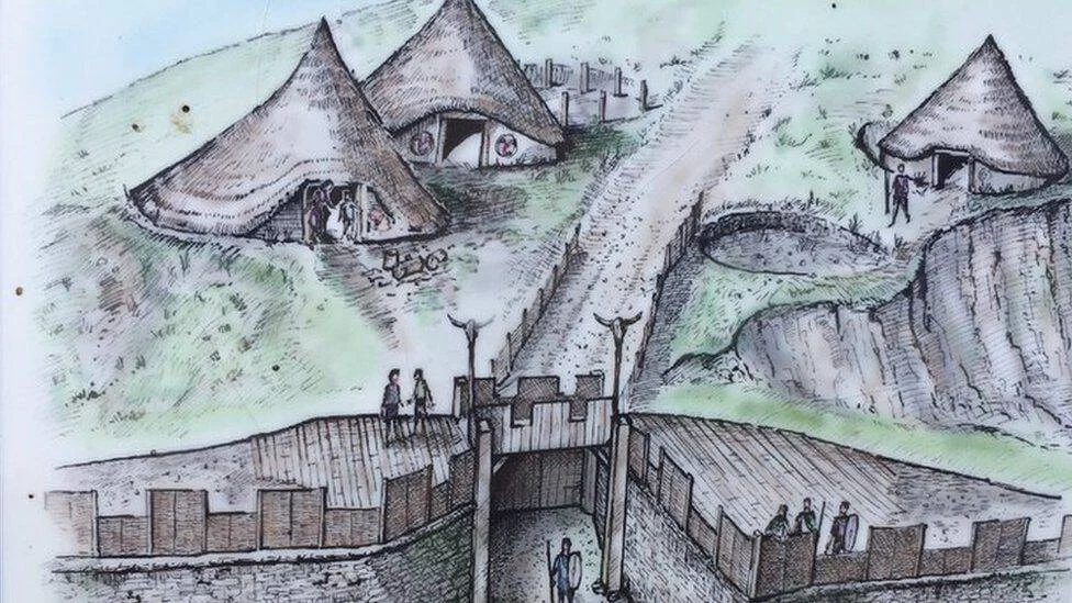 Dibujo artístico que reconstruye un poblado prehistórico con cabañas de techo cónico, murallas de madera y figuras humanas en colinas.