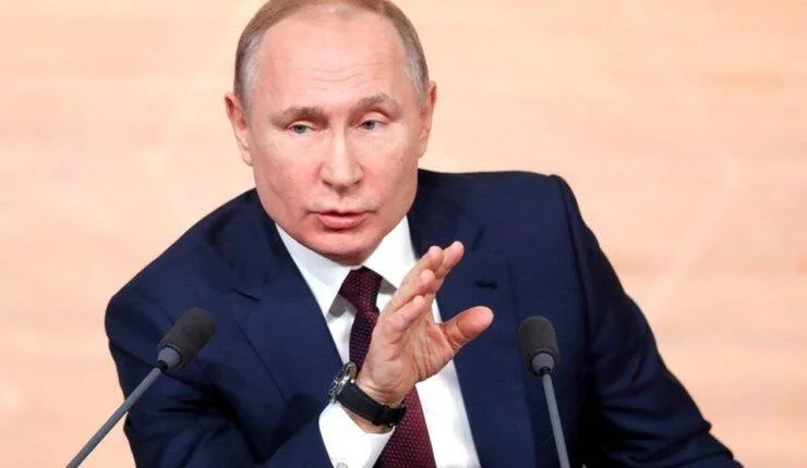 Vladimir Putin gesticula con la mano durante una conferencia de prensa frente a varios micrófonos.