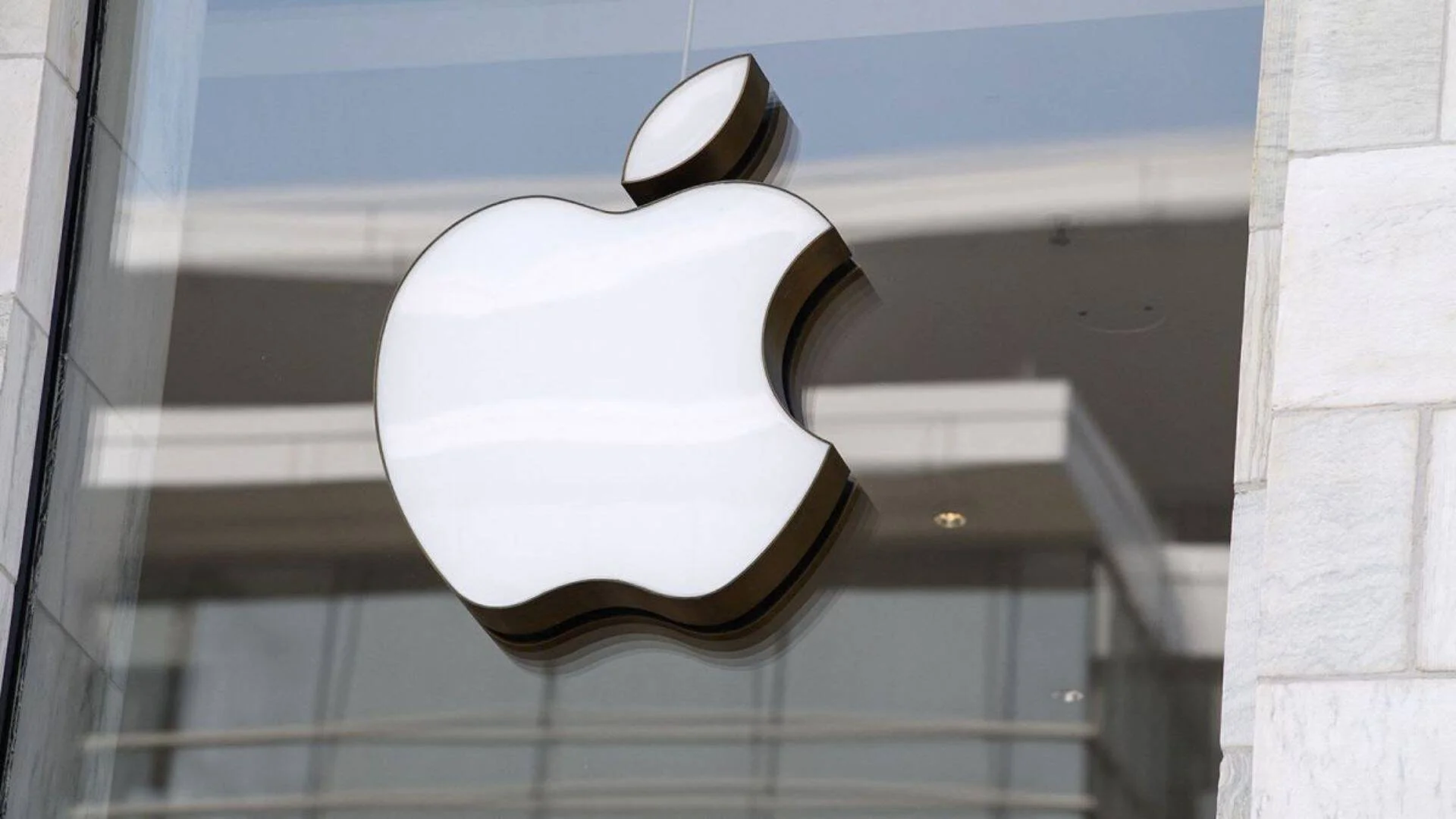 Logo iluminado de Apple sobre el vidrio de la entrada de una Apple Store.