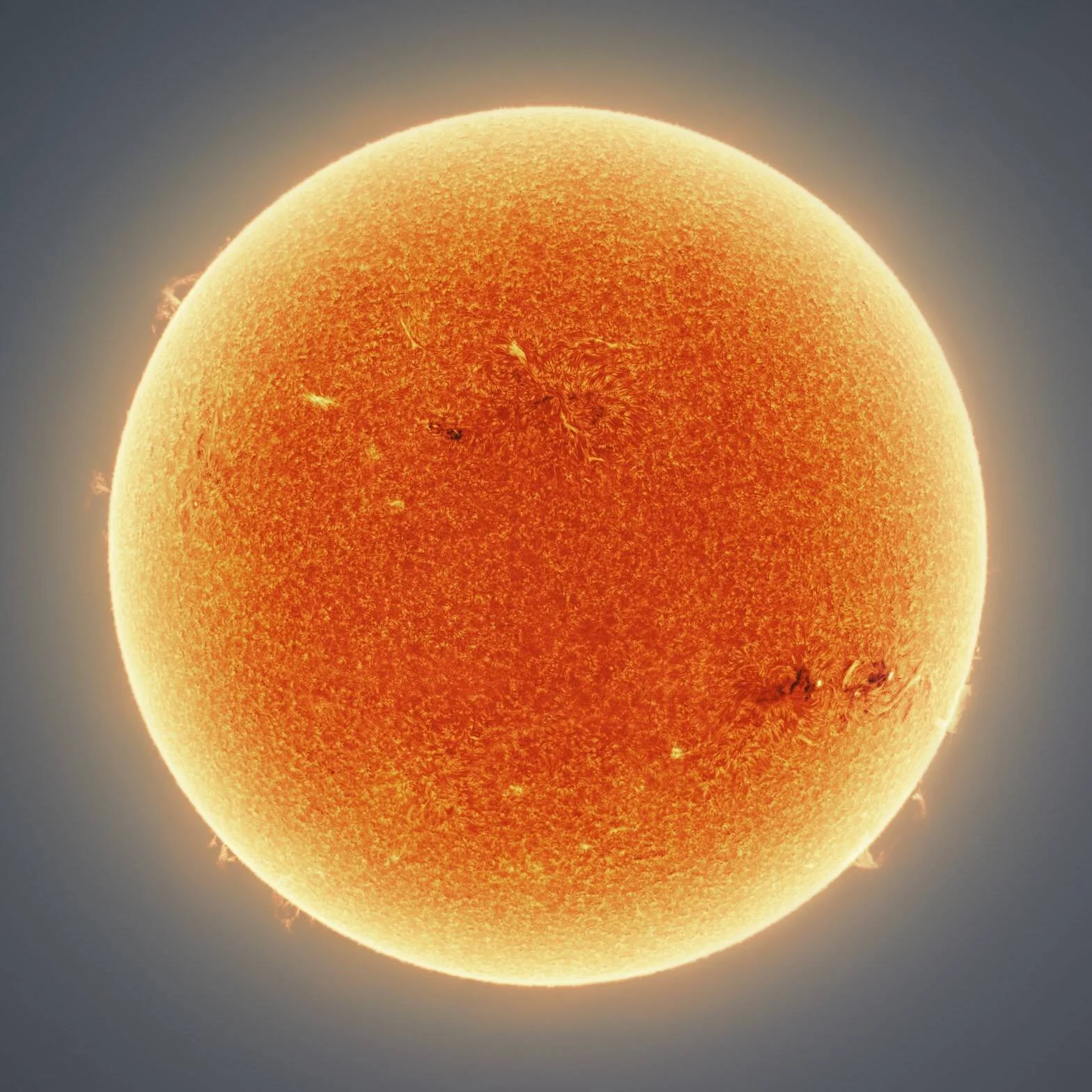 El Sol fotografiado en luz H-alfa mostrando su superficie granulada, manchas solares y prominencias en el limbo.