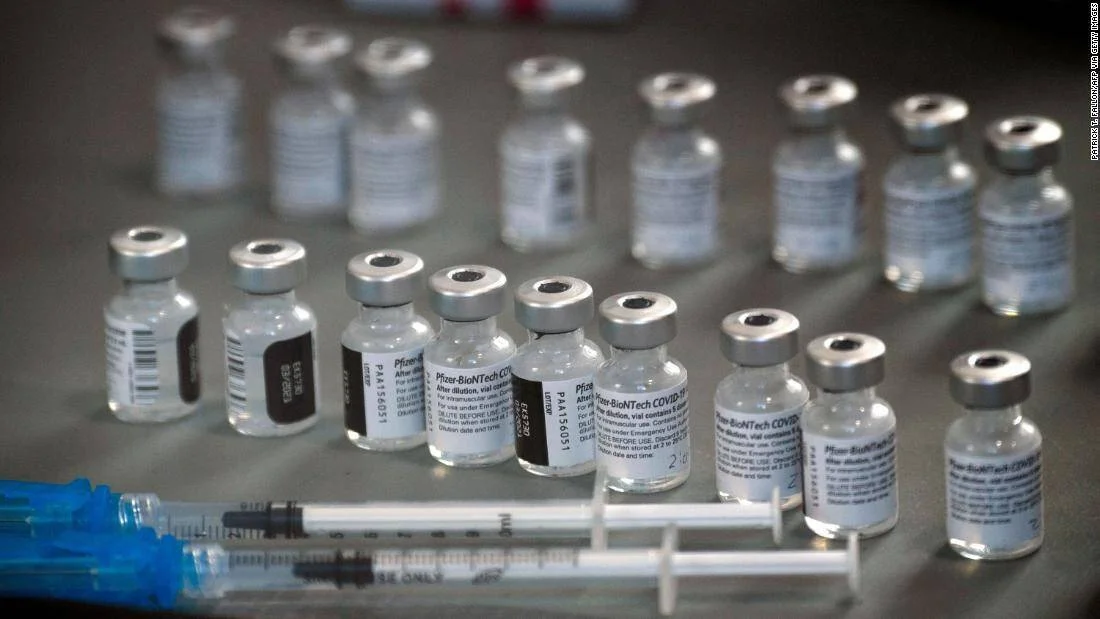 Múltiples viales de la vacuna Pfizer-BioNTech contra el COVID-19 junto a jeringas preparadas sobre una superficie.