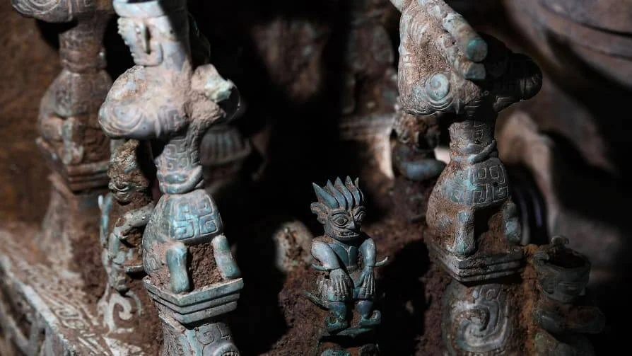 Pequeñas figuras antropomorfas de bronce con pátina verdosa recién excavadas, pertenecientes a una cultura antigua.