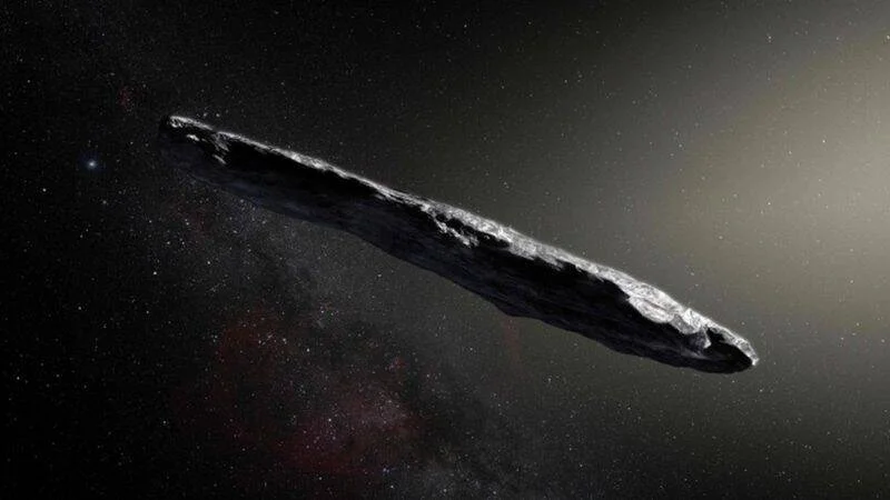 Ilustración artística de un objeto interestelar de forma alargada y rocosa atravesando el espacio con estrellas de fondo.