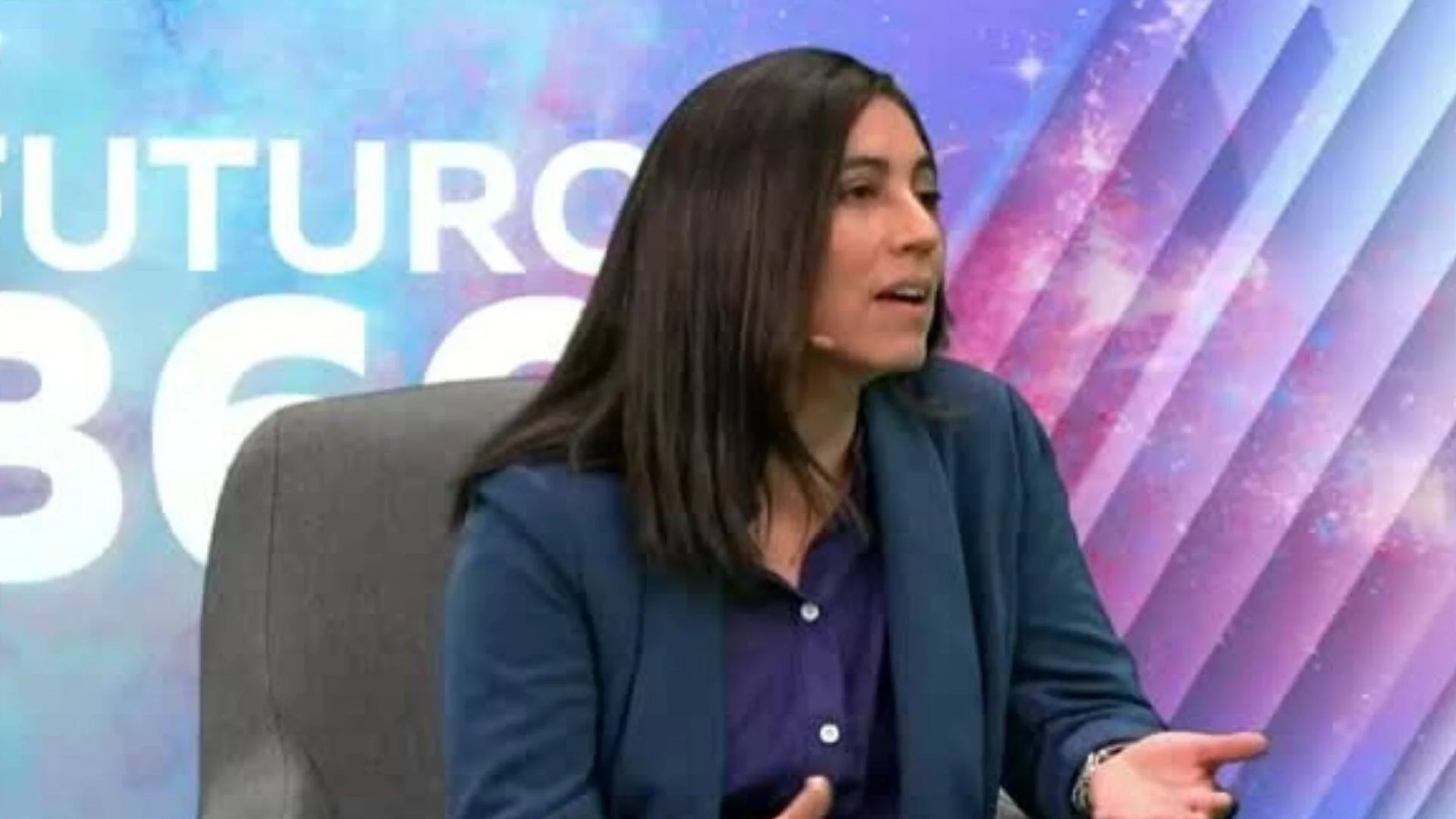 Mujer con blazer azul habla en estudio de televisión con el logo del programa Futuro 365 al fondo.