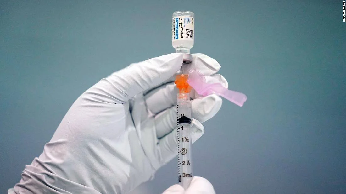 Mano con guante blanco carga una jeringa con una vacuna contra el COVID-19 desde un vial.
