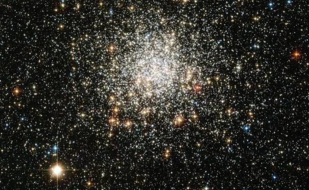 Cúmulo globular con miles de estrellas densamente concentradas en el centro, sobre fondo negro del espacio profundo.