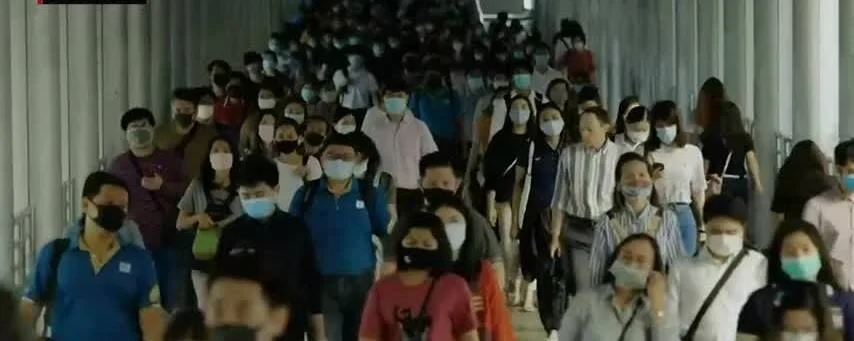 Decenas de personas con mascarillas caminan por un corredor urbano concurrido durante la pandemia.