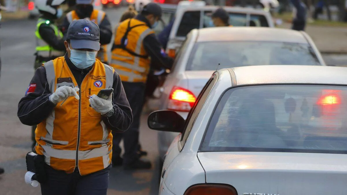Fiscalizadores del Ministerio de Transportes con mascarilla y chaleco reflectante revisan vehículos en un control de tránsito.