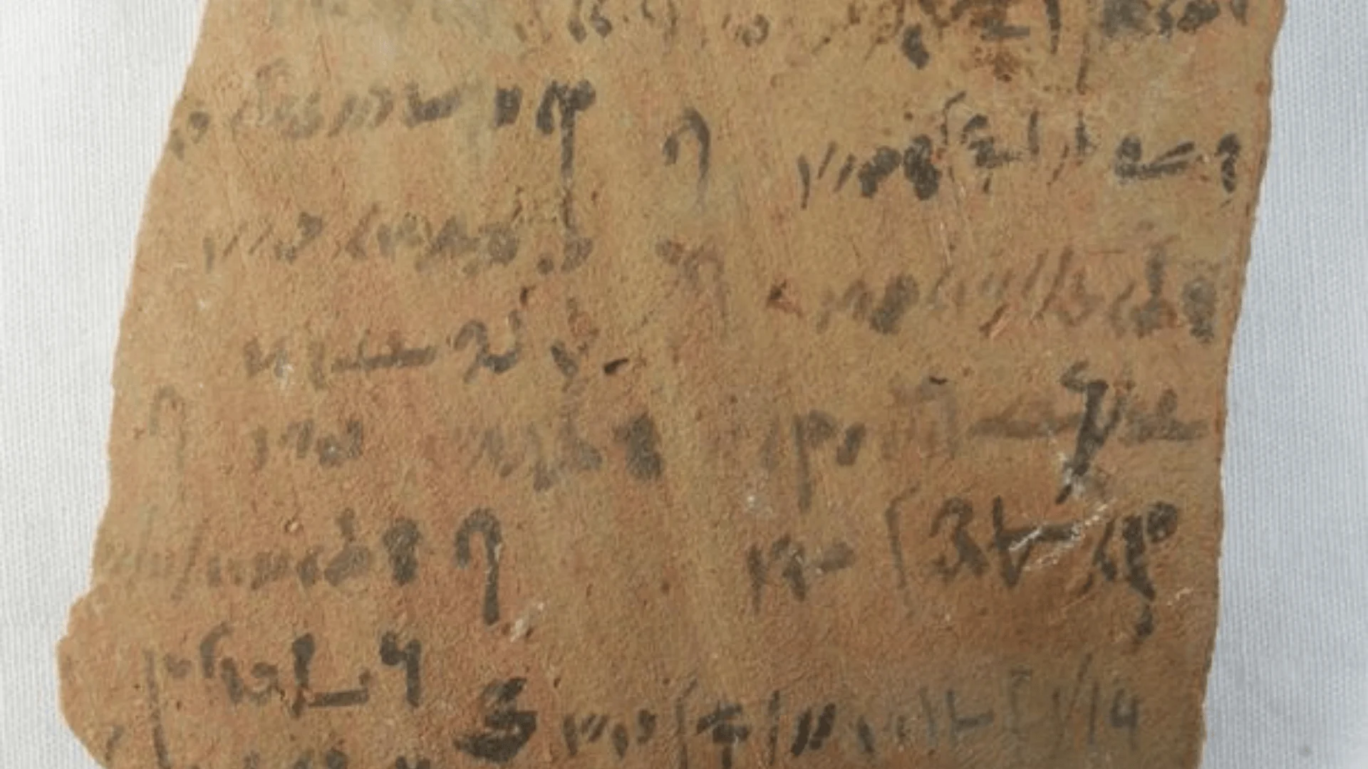 Fragmento de cerámica antiguo con inscripciones en escritura hierática o aramea trazadas en tinta negra.