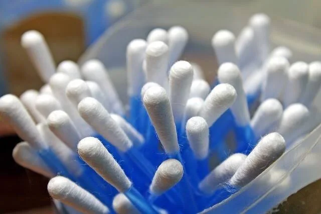 Cotonetes con punta de algodón blanco agrupados dentro de un dispensador plástico azul.