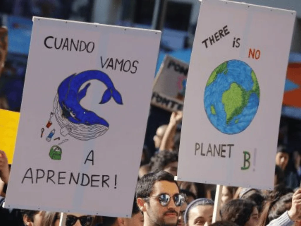 Manifestantes sostienen pancartas ecologistas: una con una ballena rodeada de plásticos y otra con el lema 'There is no planet B'.