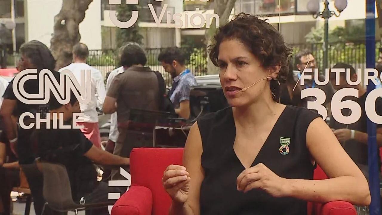 Mujer con micrófono de solapa habla en una entrevista del programa Futuro 360 de CNN Chile, sentada en una silla roja al aire libre.